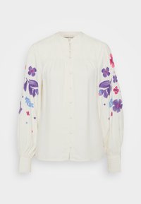Krämfärgad blus med mandarinkrage, framknäppning och långa puffärm med färgglad blommig brodyr i lila och rosa.