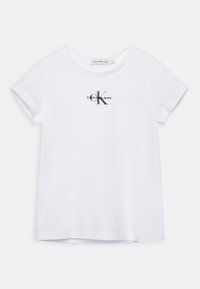 Camiseta de algodón blanca con cuello redondo y mangas cortas. Presenta un logo negro de "Calvin Klein Jeans" con una letra "K" estilizada.