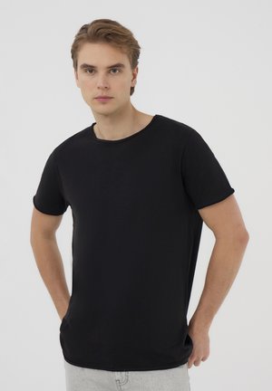 T-shirt nero a maniche corte con scollo rotondo e vestibilità comoda, realizzato in tessuto morbido. Texture liscia con orli delle maniche arrotolati.