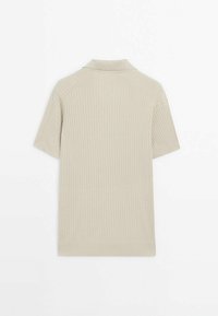 Beige, lämmin lyhythihainen polo pehmeästä neuleesta. Ominaisuuksina perinteinen kaulus ja hienovarainen yksityiskohta olkasaumoissa. Sileä pinta.