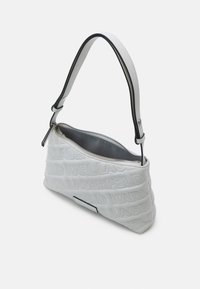Sac à main matelassé blanc avec texte embossé "KARL LAGERFELD", bandoulière bordée de noir et fermeture éclair partiellement ouverte sur le dessus.