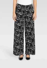 Pantaloni a gamba larga realizzati in tessuto morbido, con uno sfondo nero e un motivo di disegno a linee astratte bianche. Vita elastica per il massimo comfort.