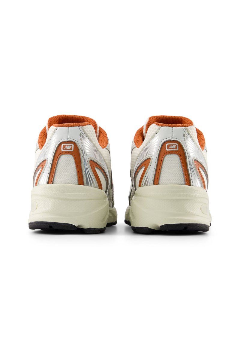 Zapatillas deportivas blancas y plateadas con detalles en naranja, parte superior de malla texturizada, suelas acolchadas y suelas exteriores de goma negra, vistas desde atrás.