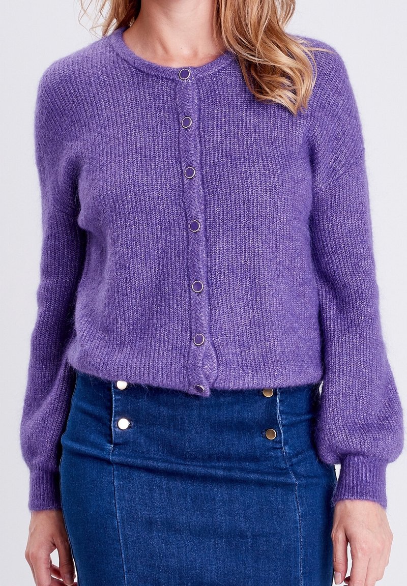 Fialový pletený kardigan s kulatým výstřihem, předním zapínáním na knoflíky a dlouhými kuličkovými rukávy, vyrobený z jemného a nadýchaného materiálu.
