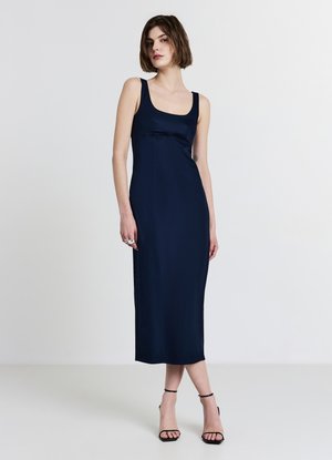 Robe ajustée en satin marine avec un décolleté en forme de rond, longueur mi-mollet et détails de coutures ; associée à des sandales à talons noires à lanières.