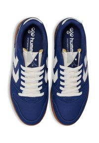 Blå sportskor med vita detaljer, texturerad syntetisk ovandel, vita snören och gummisula. Funktionen har logotypen på innersulan.