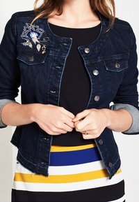Dark denim jacket with a fitted design, featuring silver buttons and light-gray rolled sleeves. It has floral embroidery on the left shoulder.