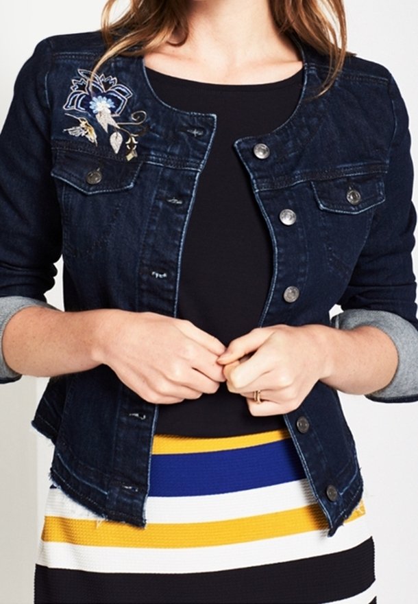 Dark denim jacket with a fitted design, featuring silver buttons and light-gray rolled sleeves. It has floral embroidery on the left shoulder.