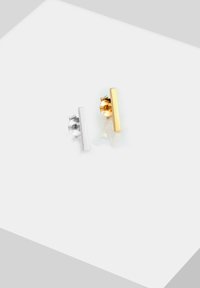Pendientes de barras de plata y oro con un diseño minimalista; plata a la izquierda, oro a la derecha, cada uno con un respaldo texturizado para un cierre seguro.