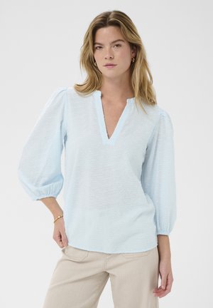 Svetlomodrá blúzka so vzorom textúrovaných prúžkov, s výstrihom do V a elastickými trojštvrťovými rukávmi. Mäkká, priedušná látka.