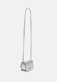 Piccola borsa a tracolla argento trapuntata con una lunga catena metallica che pende su uno sfondo bianco semplice.