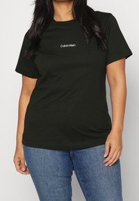 Svart bomullströja med korta ärmar och rund halsringning. Har en liten vit "Calvin Klein"-logotyp på bröstet. Avslappnad passform.