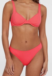 Korall színű bikini szett, párnázott, drótozott melltartóval, széles pántokkal és illeszkedő, alacsony derekú alsó résszel. Simító, rugalmas anyag, minimális varrásokkal.