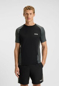 Svart idrottströja med korta ärmar, grå detaljer och "BOSS"-logotyp. Matchad med svarta shorts med logodetalj och sidostrickor.