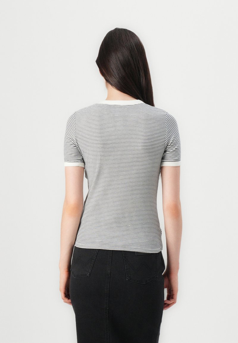 Czarna i biała, w paski, koszulka krótki rękaw z okrągłym dekoltem i kontrastowymi mankietami, zestawiona z czarną spódnicą dżinsową.