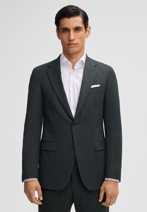 Dunkelgraue Anzugjacke mit einfachem Design, zwei Knöpfen und eingestickten Revers. Darunter ein weißes Hemd mit einer Brusttasche.