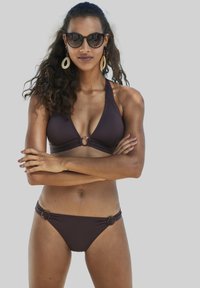 Donkerbruine bikini set met een driehoekstop met een centrale ringdetail en zijringen op de broekjes, gemaakt van een gladde stof.