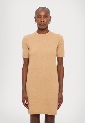 Robe en tricot à manches courtes couleur brun clair. Texture douce, col rond et silhouette ajustée, se terminant au-dessus des genoux. Pas de motifs visibles.