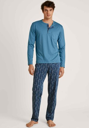 Langärmliges blaues Schlafanzugoberteil mit einer Tasche und blauen Hosen mit einem korallenähnlichen Muster. Der Stoff ist weich mit einer glatten Textur.