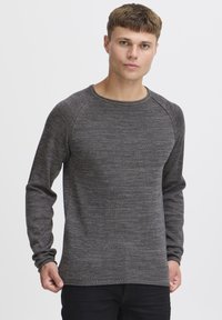 Sweatshirt à col ras du cou en gris foncé à manches longues, avec un tricot texturé, des manches raglan et une coupe décontractée. L'ourlet est cousu.