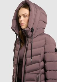 Pūka jaka mīksts mauve tonī, ar lielu kapuci, rāvējslēdzēju un ribotu tekstūru. Regulējami auklas un logo uzlikums uz piedurknes.