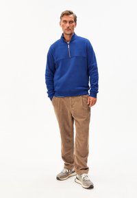 Blauwe zip-up sweatshirts met een ronde hals, gecombineerd met lichtbruine corduroypantalons en grijze sneakers. Casual pasvorm en getextureerde stof.