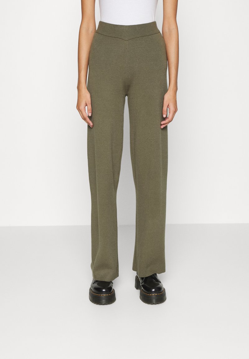 Calças largas em verde-oliva, feitas de um tecido de malha, com uma cintura alta e sem fechos ou bolsos visíveis.