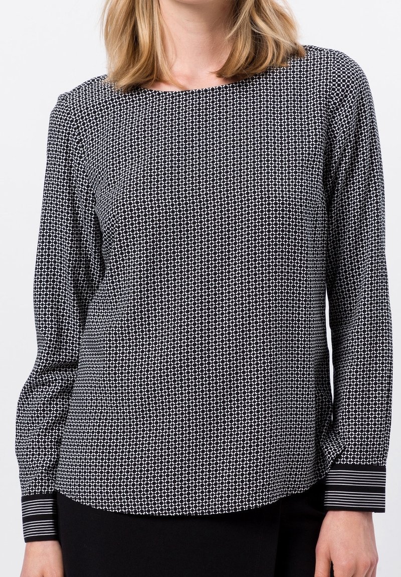 Schwarz-weiß gemusterte Bluse mit langen Ärmeln, Rundhalsausschnitt und gestreiften Manschetten. Leichter Stoff mit glatter Textur.