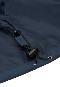 Laivastonsininen kangas, jossa on kiristysnyöri mustalla lukolla ja messinkinen silmukka, korostaa sileää, synteettistä pintaa.