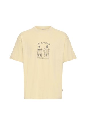Kermanvärinen puuvillainen t-paita, jossa on lyhyet hihat ja etupuolella grafiikka kahdesta ihmisestä tuoleissa sekä tekstissä "Take it Outside" yläpuolella.