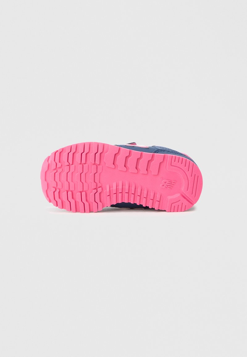 Suela de zapato con un patrón de tread rugoso en goma de color rosa brillante, que muestra durabilidad y tracción, con una sección superior azul parcialmente visible.