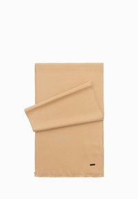 Beige tørklæde lavet af blødt stof, med rå kanter og et lille, sort rektangulært mærke i den ene ende. Flad liggende stil.