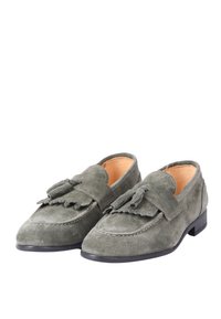 Mocassini in suede verde oliva con dettaglio a nappina sulla tomaia, caratterizzati da una punta rotonda e un tacco nero basso. Fodera interna liscia.