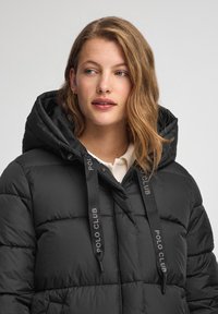 Czarna puchowa kurtka z kapturem, o pikowanym wzorze i sznurkami z logo "POLO CLUB". Gładka tekstura, rękawy o średniej długości.