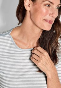 Gestreiftes hellgraues und weißes Oberteil mit rundem Ausschnitt, das eine weiche Textur und einen hellblauen Besatz entlang des Kragens aufweist.