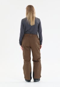 Bruine sneeuwbroeken met een ontspannen pasvorm, een hoge taille, zwarte accenten bij de enkels en een gladde, waterafstotende textuur.