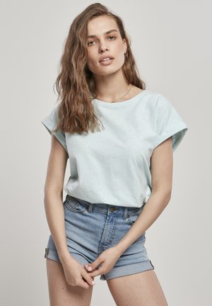 Blusa azzurro chiaro a maniche corte con una texture morbida, scollo rotondo e polsini arrotolati, abbinata a pantaloni shorts in denim a vita alta.