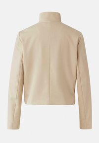 Beżowa, dopasowana marynarka z wysokim kołnierzem, usztywnionymi ramionami i gładkim tyłem. Wykonana z gładkiej tkaniny, posiada długie rękawy.