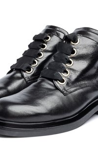 Black leather ankle boots featuring a glossy finish, ribbon laces, and gold-tone eyelets. Rounded toe and flat rubber sole.