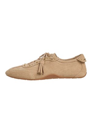 Chaussure plate en daim beige avec lacets à l'avant, détail pompon et petits clous dorés le long des bords et de la languette de talon.