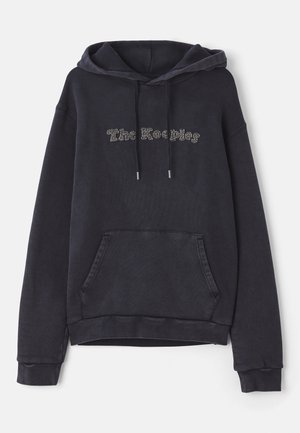 Dark gray hoodie featuring a front pocket, drawstrings, and "The Keepers" text design in light embellishments. Soft, textured fabric.