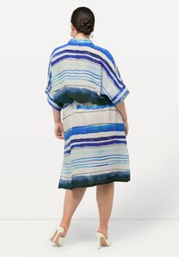 Vestido holgado con rayas horizontales azules y verdes, mangas cortas y un dobladillo que cae por encima de la rodilla. Textura de tela suave.