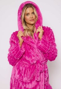 Fluffy roze badjas met een capuchon, vervaardigd van een pluche stof, met tekstuurlijnen en een riemsluiting. Lange mouwen en een zachte, comfortabele uitstraling.