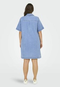 Jeanskjolsklänning i ljusblått med vita vertikala ränder, korta ärmar, krage och en bakfålla. Slät textur med en avslappnad passform.