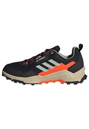 Czarno-pomaranczowy but do biegania terenowego Adidas Terrex z beżową podeszwą, odblaskowymi paskami po bokach i wytrzymałą bieżnią do użytku na zewnątrz.