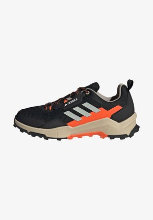 Czarno-pomaranczowy but do biegania terenowego Adidas Terrex z beżową podeszwą, odblaskowymi paskami po bokach i wytrzymałą bieżnią do użytku na zewnątrz.