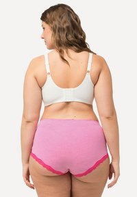 Soutien-gorge blanc avec bretelles réglables et fermeture à crochets, associé à une culotte rayée rose avec des bordures en dentelle rose.