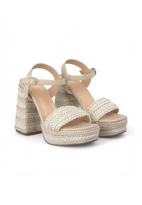 Sandalias de plataforma de esparto beige con textura trenzada, punta abierta, correa al tobillo y tacón cuadrado que cuenta con detalles tejidos y acentos sutiles.