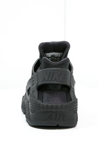 Svarta Nike-löparskor med en texturerad sula, vadderad krage, framträdande logotyp och en minimalistisk design som fokuserar på ventilation och komfort.