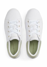 Sneakers bianchi con occhielli oro, dettagli testurizzati verdi sul tallone e una superficie liscia. Presentano laccetti e un interno imbottito.